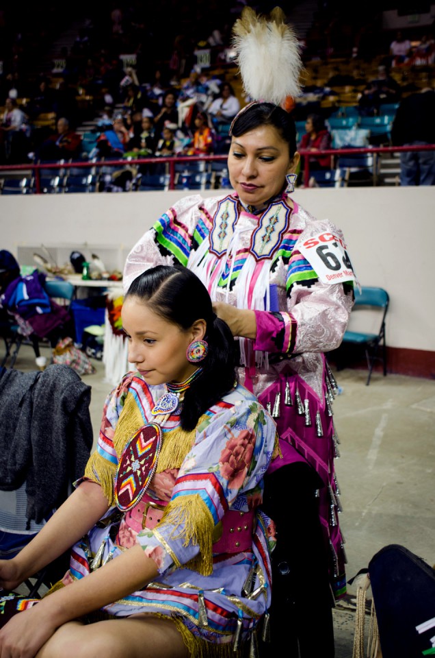 Hailing from the Pine Ridge Reservation in South Dakota, women share a moment together while preparing their dance regalia.