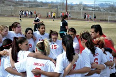 Ignacio's newest girls' soccer head coach, Oscar Cosio (right, red shirt), wraps up his first pre-match speech in the huddle as the black-clad Pagosa Springs Lady Pirates await the 2013 season's kickoff on IHS Field March 19.