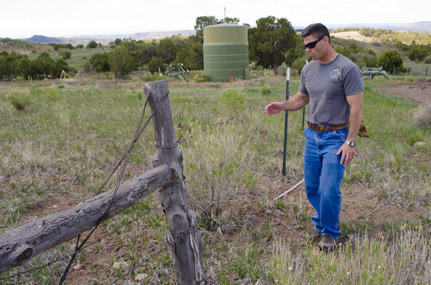 Project manager Bill Gwinn illustrates the disrepair of aging fenceline.