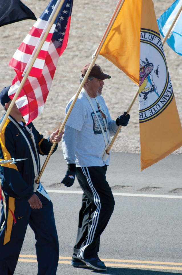 Southern Ute veteran Dewitte Baker carries the Southern Ute tribal flag
