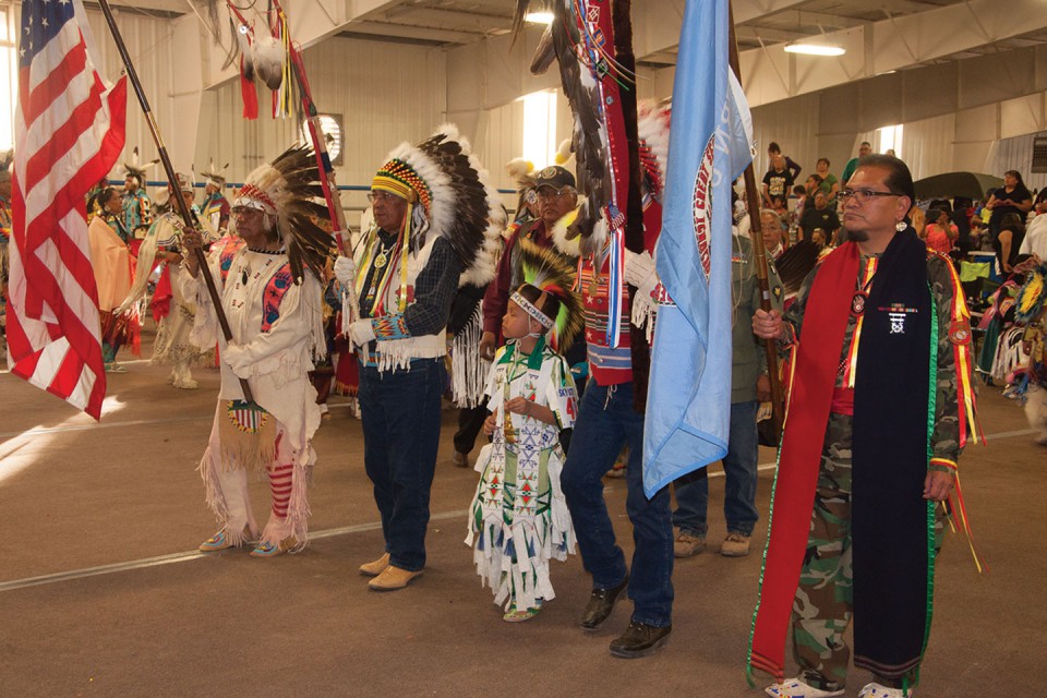Southern Ute veteran Austin Box carrying the United States flag and Southern Ute veteran Jack Frost Jr. carrying the Southern Ute tribal flag bookend the eagle staffs during a grand entry of the Southern Ute Bear Dance Powwow on Saturday, May 25 at the Sky Ute Fairgrounds.