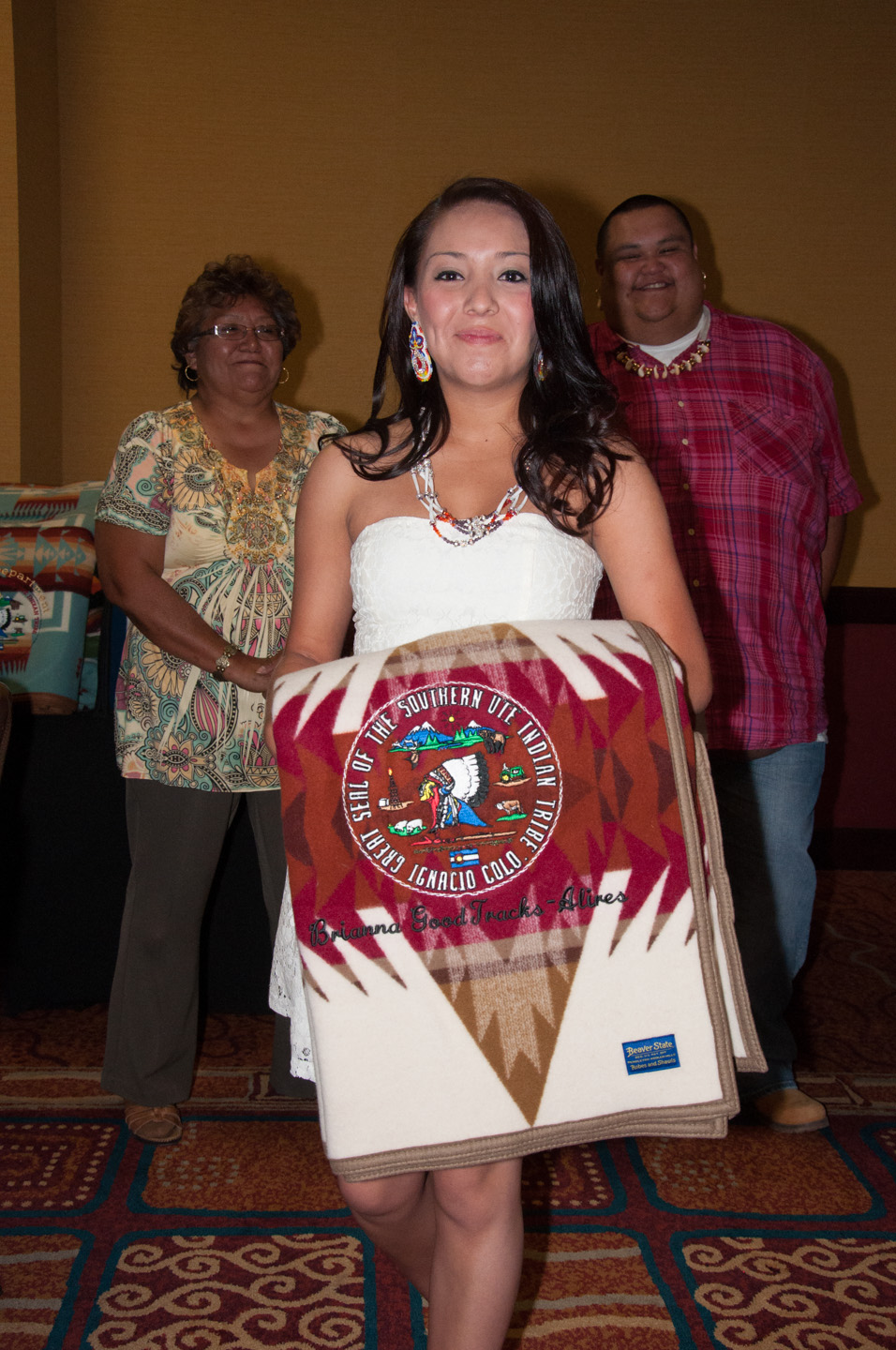Bayfield High School graduate Brianna Goodtracks-Alires accepts a Pendleton blanket from Southern Ute Indian Tribal Council Lady Ramona Y. Eagle (left) and Chairman Jimmy R. Newton Jr. (right) during the Education & Johnson O’Malley Annual Banquet on Saturday, June 22 at the Sky Ute Casino Resort.
