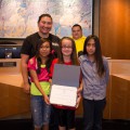 Thumbnail image of Crystal Garnanez of the Southern Ute Police Department poses with club members for a photo with the certificate of recognition from the U.S. Department of Health and Human Services.