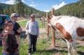 Thumbnail image of Lands Division Head Germaine Ewing (left) and Range Division Head Jason Mietchen (second from left) catch up with tribal member Winterfawn Rey, with the scenic ranch property in the background.