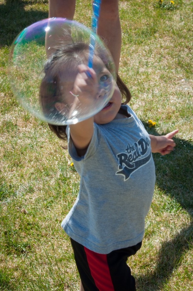 A little one reaches for a big bubble.