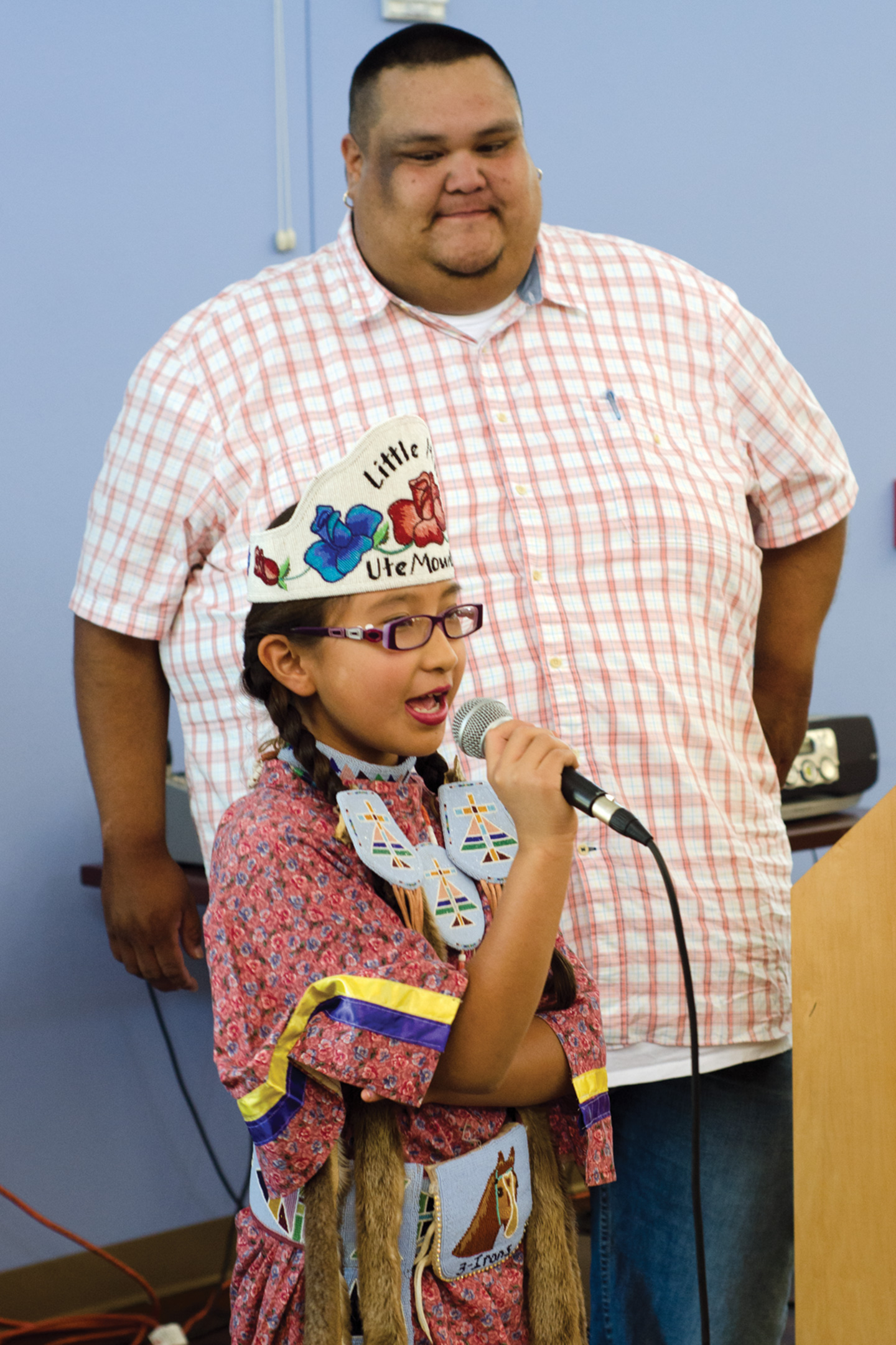 Southern Ute Chairman Jimmy R. Newton Jr. listens on as Little Miss Ute Mountain speaks during the Tri-Ute Games Closing Ceremony at the Multi-purpose Facility on Thursday, July 25.