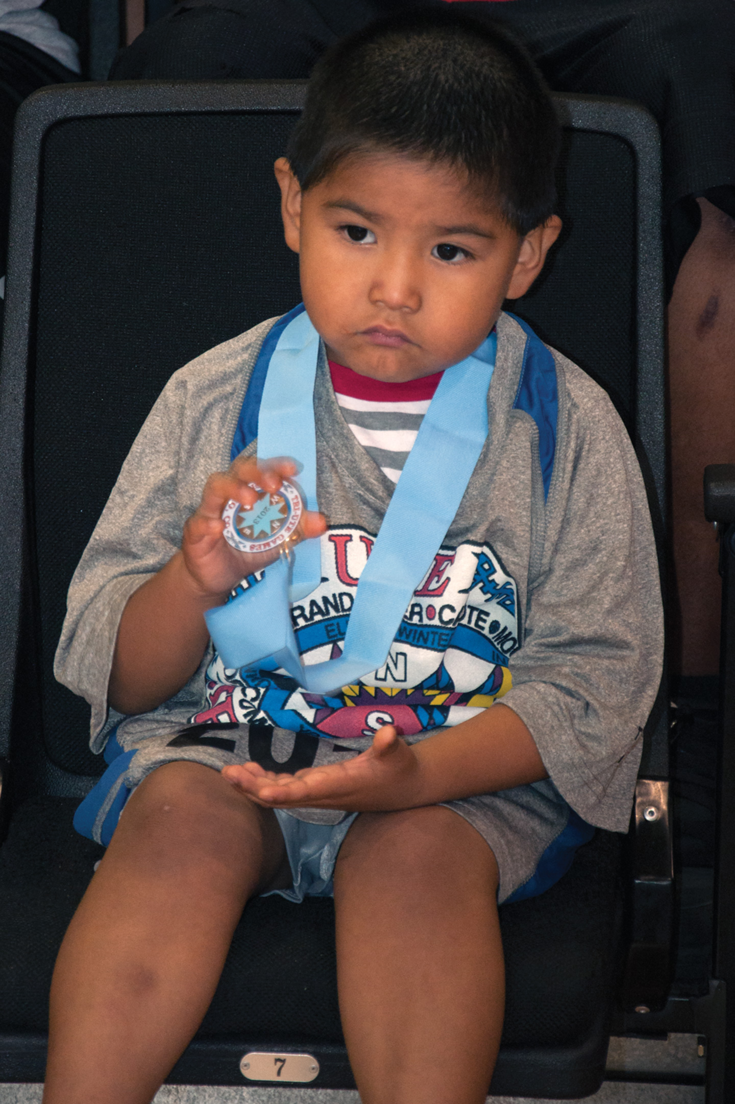 A young Southern Ute participant plays with his medal.