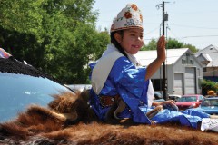 Little Miss Southern Ute, Ollyvia Howe beams in the morning sunlight as she waves to the crowd gathered along Main Street in Ignacio, Saturday, July 26.