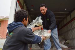 Jay Morgan helps Isaac Rodriguez from Acumen Environmental Services load a bag of extracted asbestos from the Southern Ute Annex Building.