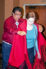 During the quarterly Colorado Commission of Indian Affairs (CCIA) meeting in Towaoc, Colo. Ute Mountain Ute Tribal Chairman, Manuel Heart puts a shawl on Lt. Gov. Donna Lynne. The shawl was a gift to from the Ute Mountain Ute Tribe.