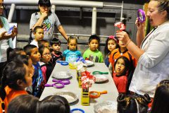 Primary kids during their adventure to the Powerhouse Science Center listen and observe what food coloring does do a flower.