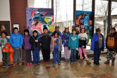 Southern Ute Indian Montessori Academy Upper Elementary students take a break from singing Christmas carols on Friday, Dec. 16 to pose in front of their paintings hanging in the Hall of Warriors. 