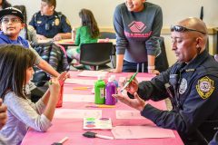 Southern Ute Police Officer, Richard Herrera paints his hand with Haiden Valdez during Craft Day hosted by the Boys and Girls Club. The Craft Day is just one way BGC is collaborating with SUPD staff to help build a supportive relationship. 