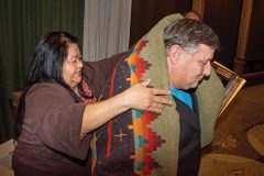 Southern Ute Vice-Chairman Cheryl Frost wraps Harley Everhart, EHS Technician III — Air Quality in a Pendleton blanket. Everhart received the first-place award for the Growth Fund’s annual Safety awards banquet. 