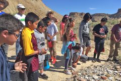 Students looking at various pottery shards at Ute Mountain Tribal Park. 
