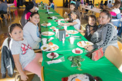 Lower elementary students, Maylana Goodtracks, Myla Goodtracks, Nevaeh Sandoval and Skydawn Baker sit together at the SUIMA Christmas lunch on Thursday, Dec. 20. 