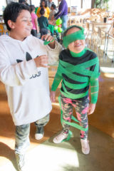 Nathaniel Baker-Valdez wraps Neeka Ryder in green streamers for the Grinch impersonation game. They try to beat the clock by getting as much of the streamers on Ryder as they can in a minute. The annual Grinch Party was held in the cafeteria of the Academy on Thursday, Dec. 20. 