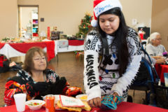 Terena Hight sets down a handmade Christmas stocking for tribal elder, San Jean Burch at the Sip, Chat and Chew held on Thursday, Dec. 20.