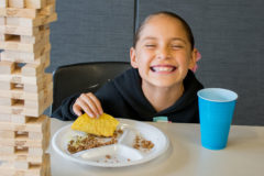 Daya Thompson shares a big smile with the camera as she finishes her turn of Jenga and starts to bite into her taco at the BGC Family Game Night on Wednesday, May 22. BGC sponsored the event and provided tacos and games for kids and their families to play. 