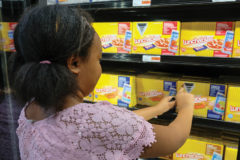 Nailah Simon places a Sticker Shock sticker on a lunchables in one of Farmers Fresh’s refrigerators on Saturday, Sept. 7.