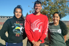 Standing with head coach Daniel Holley (center), Ignacio Girls' Cross-Country members Avaleena Nanaeto (left) and Charlize Valdez (right) brave chilly, windy conditions before practice Monday, Oct. 21, for a photo five days before both were to run in Colorado Springs, representing IHS in the 2019 CHSAA State Championships' Class 2A girls' feature.
