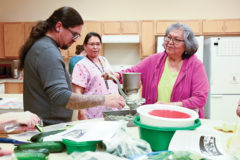 Chef Karlos Baca watches as tribal elder, Linda Eagle grinds handfuls of blue corn, so the Cooking Matters class could make fresh pressed tortillas for quesadillas and salsa.