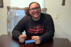 Seated Friday, May 1, at her home in Durango while following COVID-19 safety guidelines, current DHS senior Aliyana White, who attended Ignacio High her freshman and sophomore years (she first displayed her shot- and discus-throwing talents during the latter), signs via cell phone her Adams State University Track & Field commitment documents.