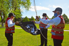 Rudley Weaver and Bruce LeClaire unfold the new Prisoner of War/Missing in Action (POW/MIA) flag as Raymond Baker holds the flag ties in preparation to raise the POW/MIA flag.