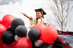 Ember Vigil blows a kiss to the families, teachers and students who watch on as the kindergarten graduates drive through the Ignacio Elementary School parking lot.  