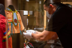Museum Collections Manager Tallias Cantsee adjusts pieces of beadwork in the latest exhibit ‘Inside Out 2.0: Native American Artists in the 21st Century’ — this exhibit is open and features art work from Southern Ute tribal members.   