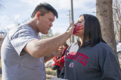 Elijah Weaver helps his sister Kalynn Weaver place a red handprint across her mouth before the Missing and Murdered Indigenous Women and Girls walk began outside the Mouache-Capote Building on Monday, Nov. 25, 2019.  