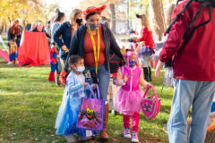 Southern Ute Indian Montessori Academy Teacher, Dawnnet Naranjo leads Angelisa Pena and Bianca Weaver through the ‘Carn-EVIL’ booths outside the Annex Building to Trick-or-Treat for goodies that led them across tribal campus. 

 