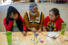 With two expert crafters, SUIMA students were able to learn two ways to tie off their choker in class, Friday, Nov. 19. Council Member Linda Baker shows students how her mother and grandmother taught her to complete the choker.  