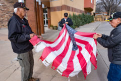 Members of the Southern Ute Veterans Association, Commander Howard Richards Sr., Treasurer Bruce LeClair, and Rod Grove take down a tattered flag at the Ignacio Community Library.  