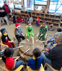 SUIMA Primary boys gather around the drum and sing songs with Southern Ute elder, Hanley Frost.