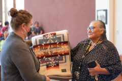 Southern Ute Tribal Services Director, Shannon Eastwood gives Southern Ute tribal elder, and retiree, Gloria Frost an embroidered Pendleton Blanket with Frost’s total years of employment and name on Wednesday, May 25 in the Hall of Warriors, in the Leonard C. Burch Building. Friends, family, and tribal employees joined together to celebrate Frost and her outstanding work ethic. Attendees enjoyed light refreshments and cake at the conclusion of the celebration.  