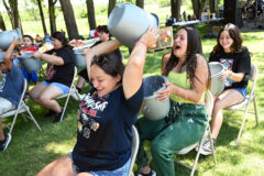 Sierra Red attempts to fill Harmony Reynolds’ bucket in the water relay, as Makayla Red awaits her turn.